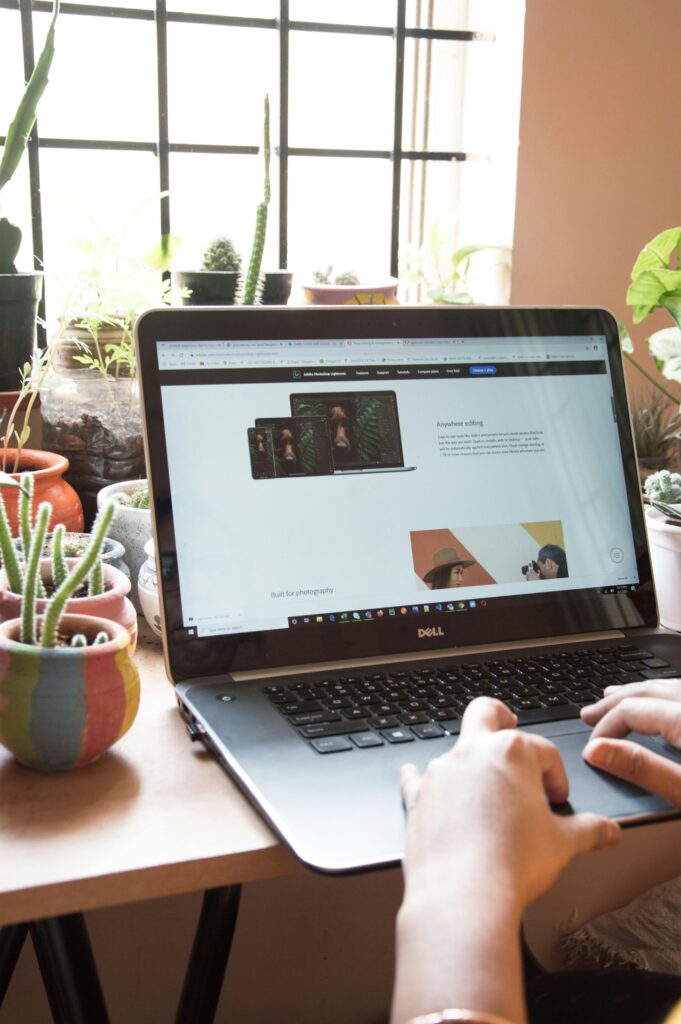 A person working on a laptop at home surrounded by potted plants, showcasing a cozy remote work environment.